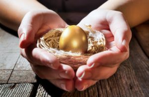 Hands holding golden egg in a birds nest